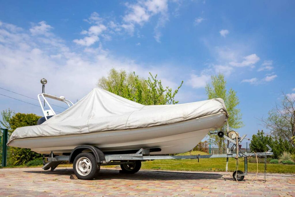 A boat sits covered in a white wrap at a vehicle storage facility.