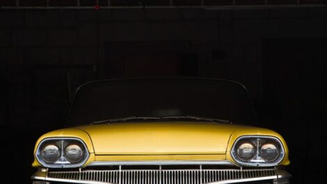 A yellow car is parked in a storage unit with a rolling door partially closed.