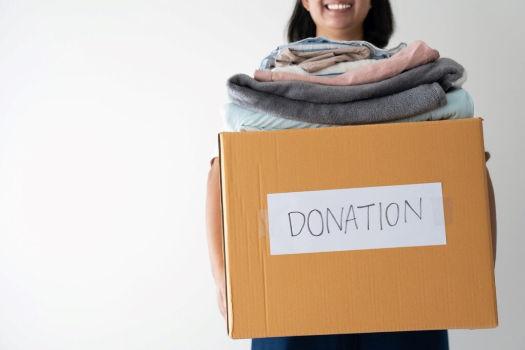 Woman holding box full of clothes for donation. 