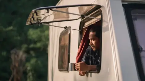 Young man looking out of RV window.