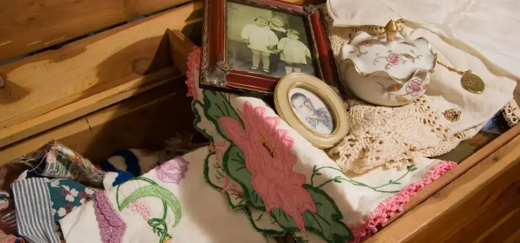 A view of a wooden storage bench holding family heirlooms, frames, and fabrics.