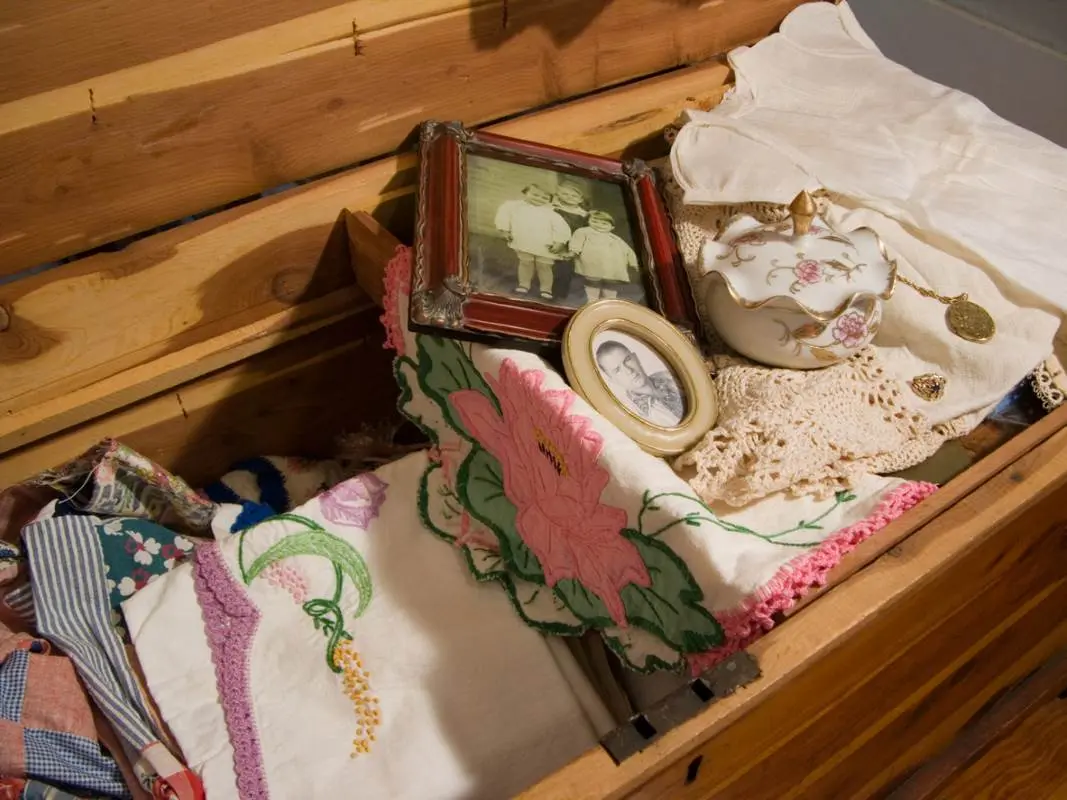 A view of a wooden storage bench holding family heirlooms, frames, and fabrics.