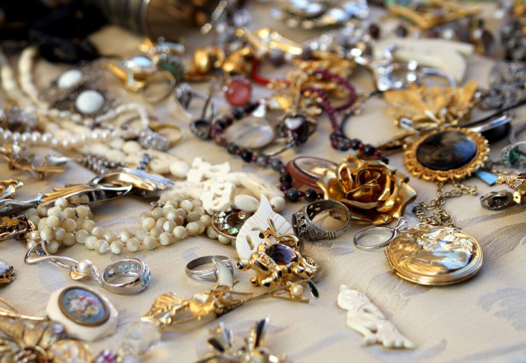 A collection of antique jewelry arranged on a white tablecloth at a sale. 