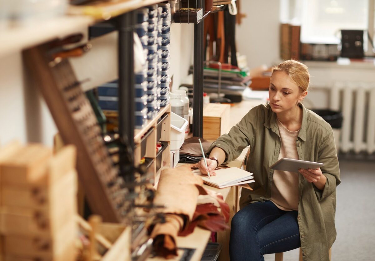 An artist drafts her next project on a wooden craft table.