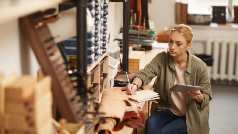 An artist drafts her next project on a wooden craft table.