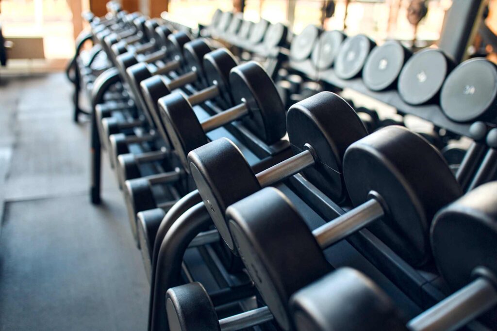 A rack of dumbbells sitting against a mirrored wall. 