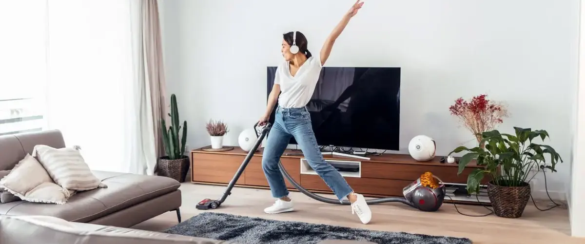 A woman enjoys vacuuming her living room while listening to music.