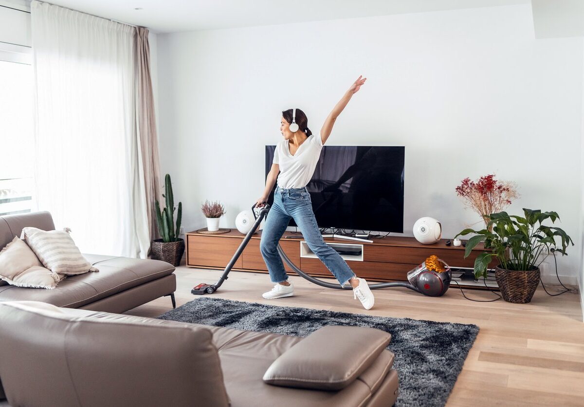 A woman enjoys vacuuming her living room while listening to music.