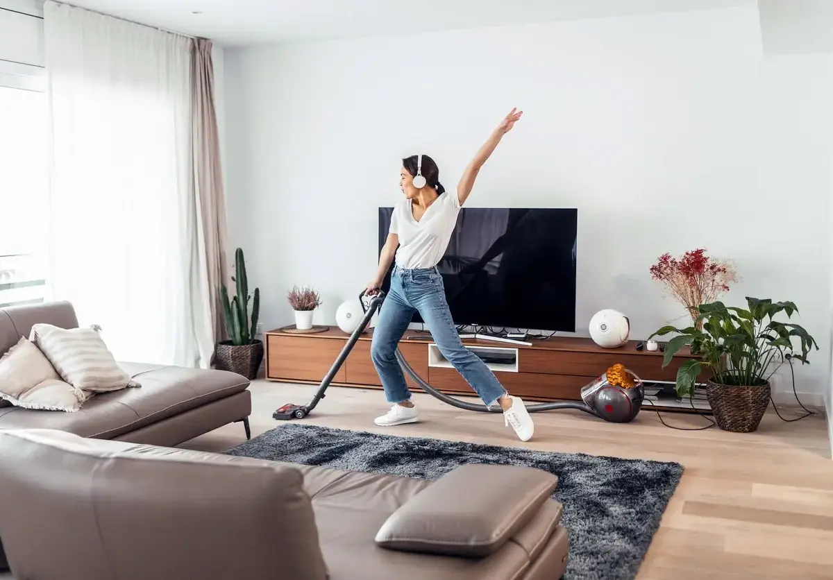 A woman enjoys vacuuming her living room while listening to music.