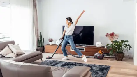 A woman enjoys vacuuming her living room while listening to music.