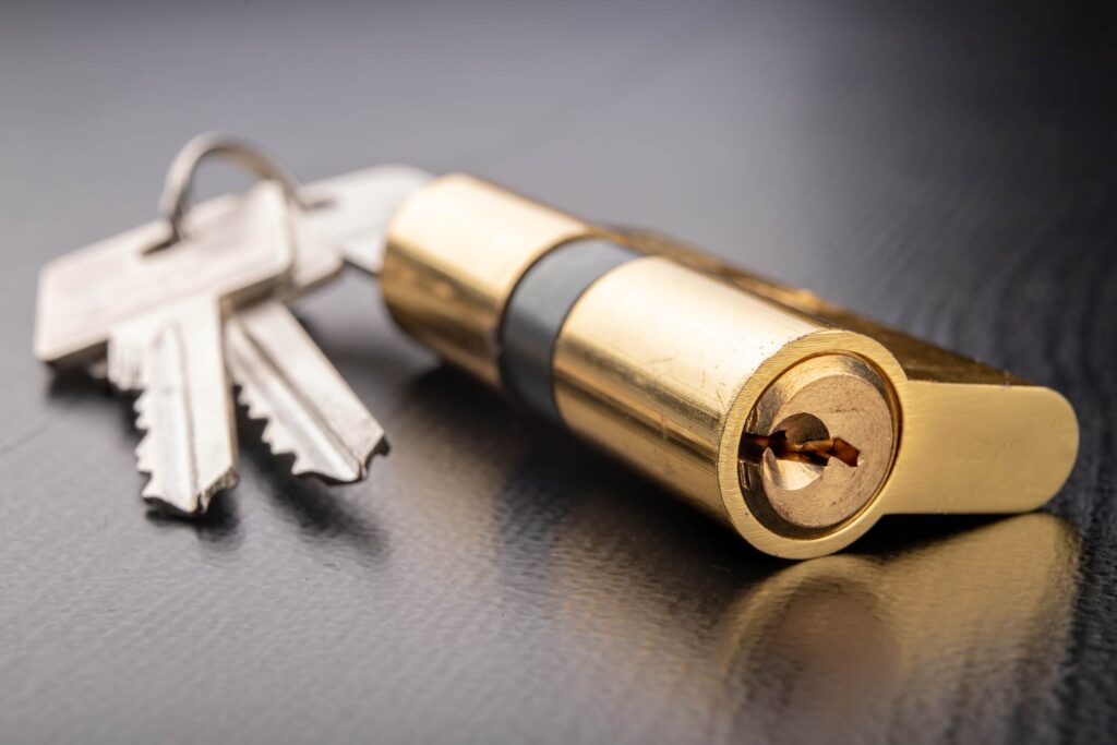 A brass cylinder door lock on a table with its keys 