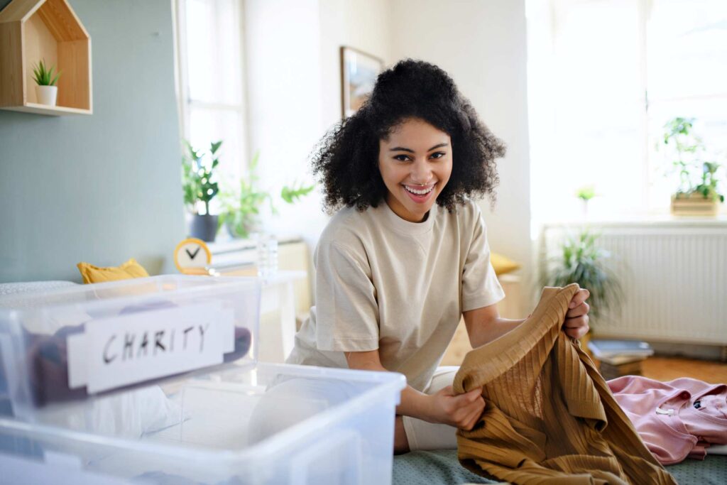 A happy woman sorts her clothing into bins for self storage.