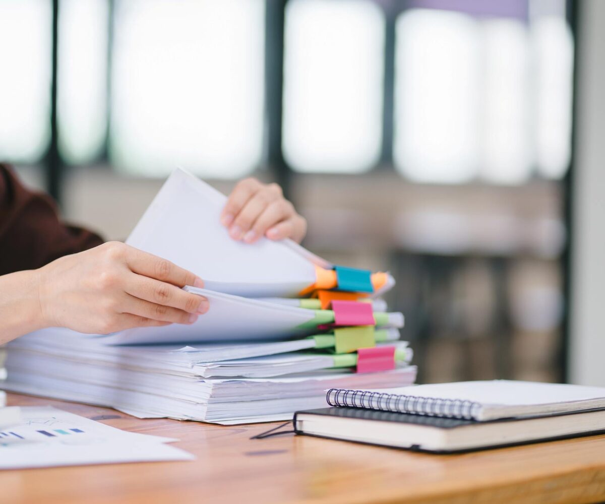 A woman sorting through files with colorful binder clips during an audit