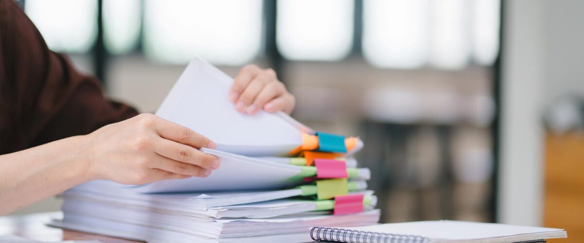 A woman sorting through files with colorful binder clips during an audit