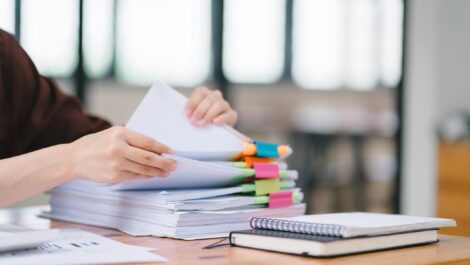 A woman sorting through files with colorful binder clips during an audit