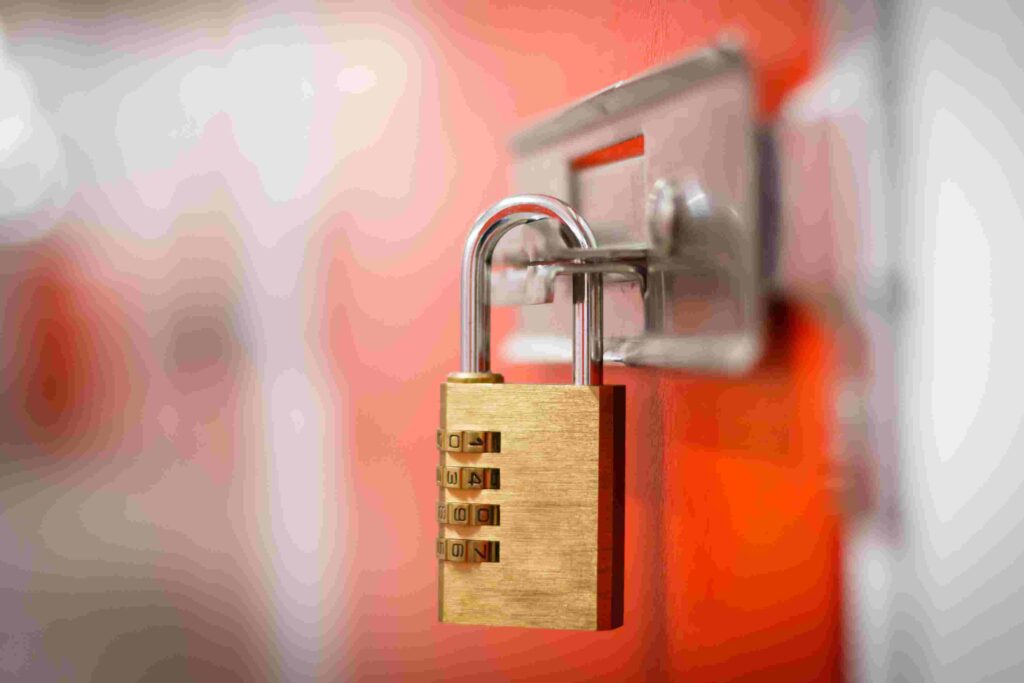 A brass combination padlock on the latch of an orange door