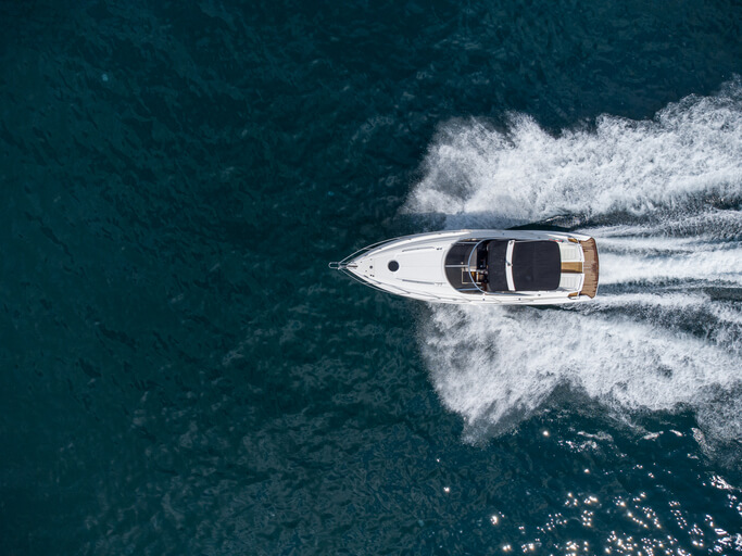 A motor boat speeds through the water, creating a large wake.