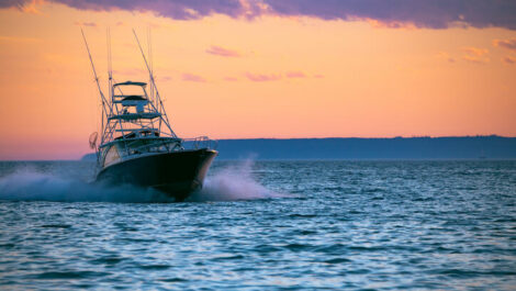 A boat cruising the water at sunset.