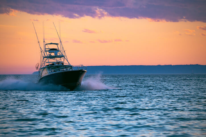 A boat cruising the water at sunset.