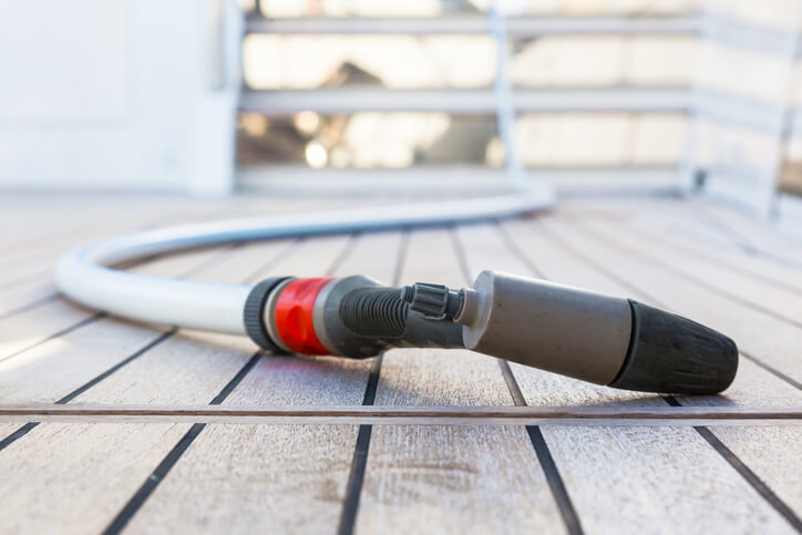 A hose lying on the deck of a boat, ready to clean it.
