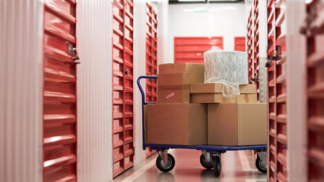 A cart with cardboard boxes sits in the hallway of an indoor storage facility.