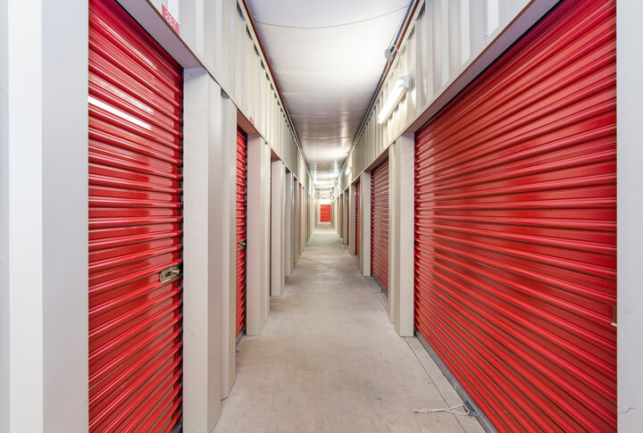 A row of red indoor storage units down a long hallway.