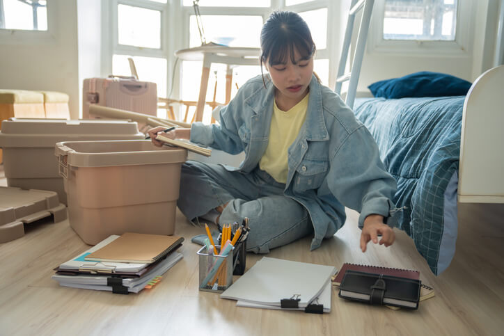 A young woman going over her checklist for dorm essentials as she prepares to move into the dorms.