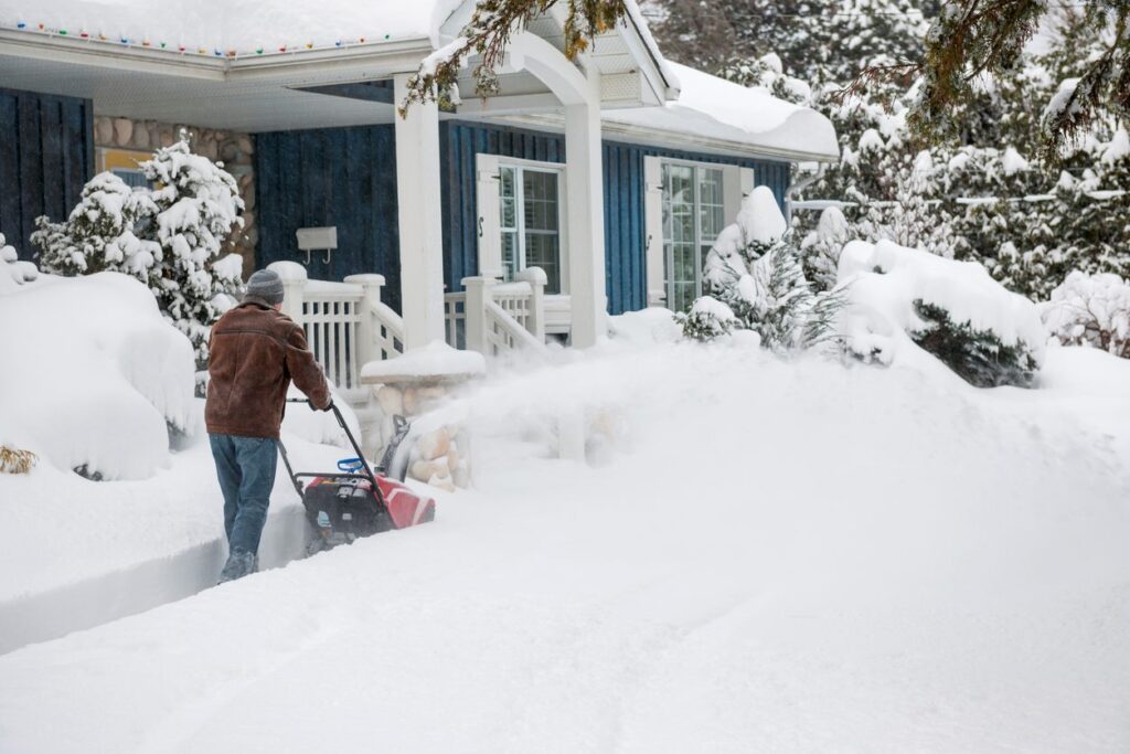 A smiling family in winter coats and hats loads the trunk of their vehicle with moving boxes in the winter.