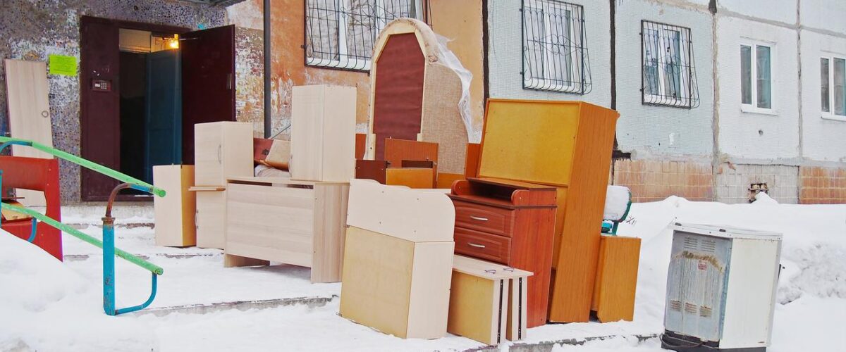 A pile of boxes and pieces of furniture outside in the snow during a cold winter move.