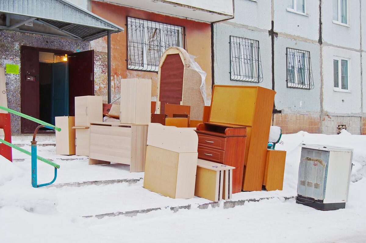 A pile of boxes and pieces of furniture outside in the snow during a cold winter move.