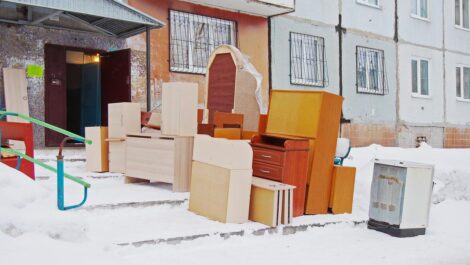 A pile of boxes and pieces of furniture outside in the snow during a cold winter move.