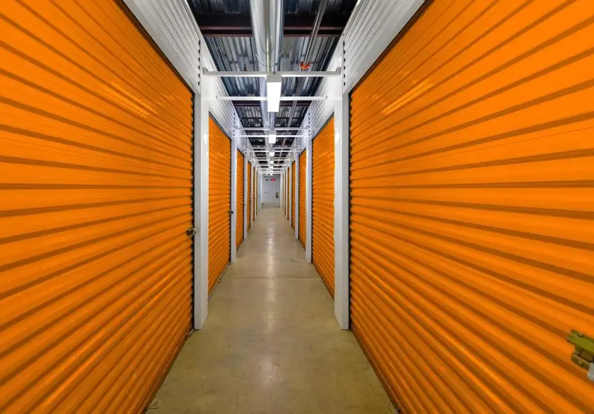 Indoor climate-controlled storage units hallway with orange roll-up doors.