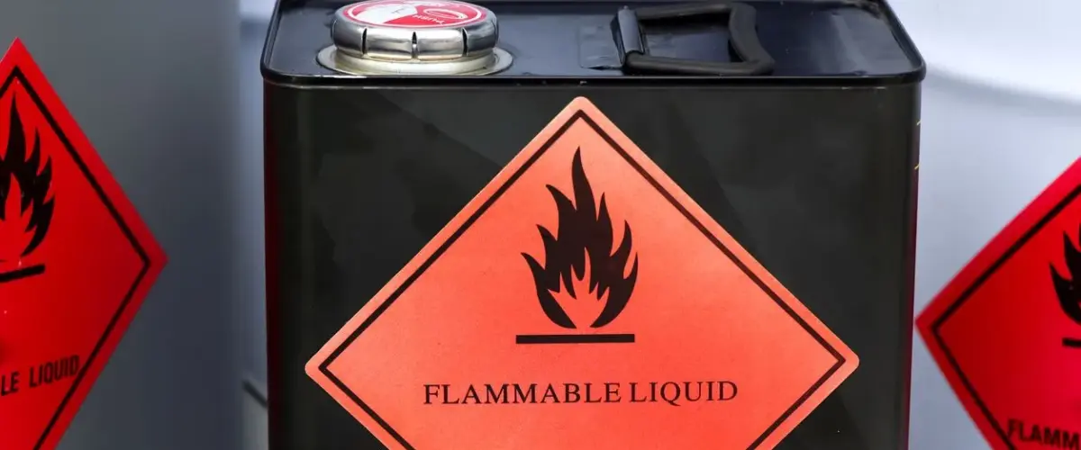 Black metal canister with a red diamond-shaped flammable liquid warning label.