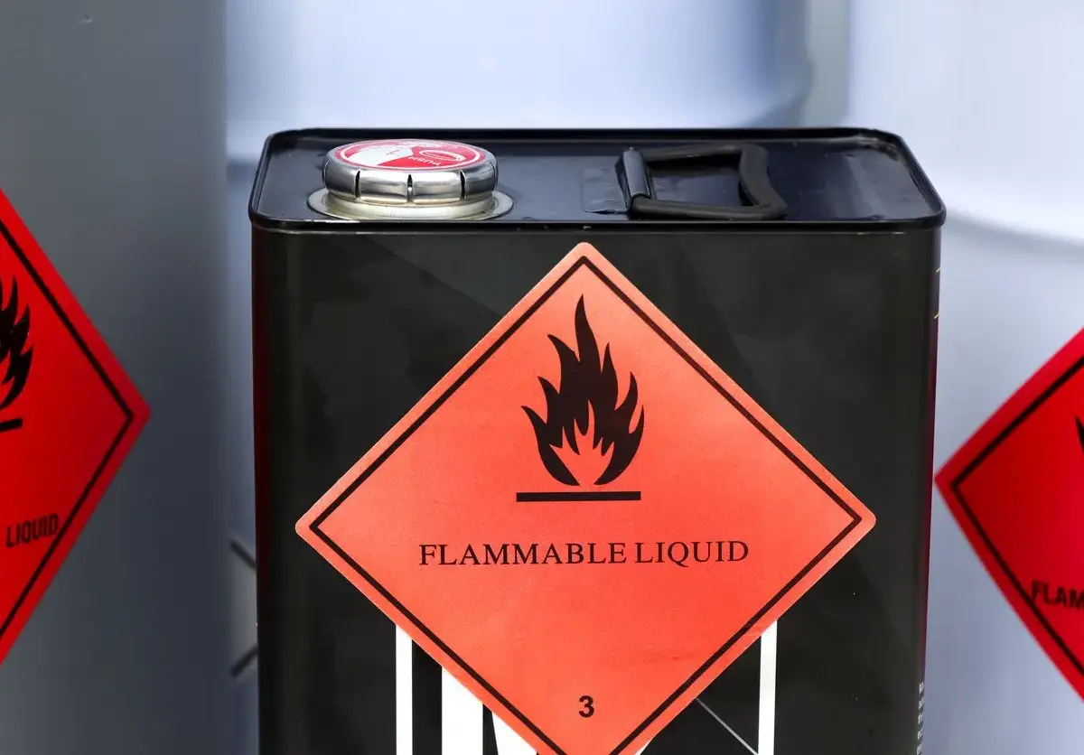Black metal canister with a red diamond-shaped flammable liquid warning label.
