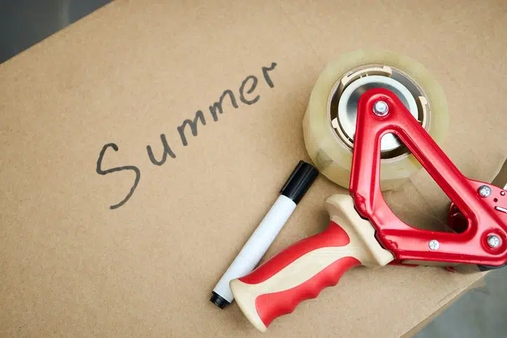 Cardboard storage box labeled 'Summer' with a marker and tape gun resting on top.